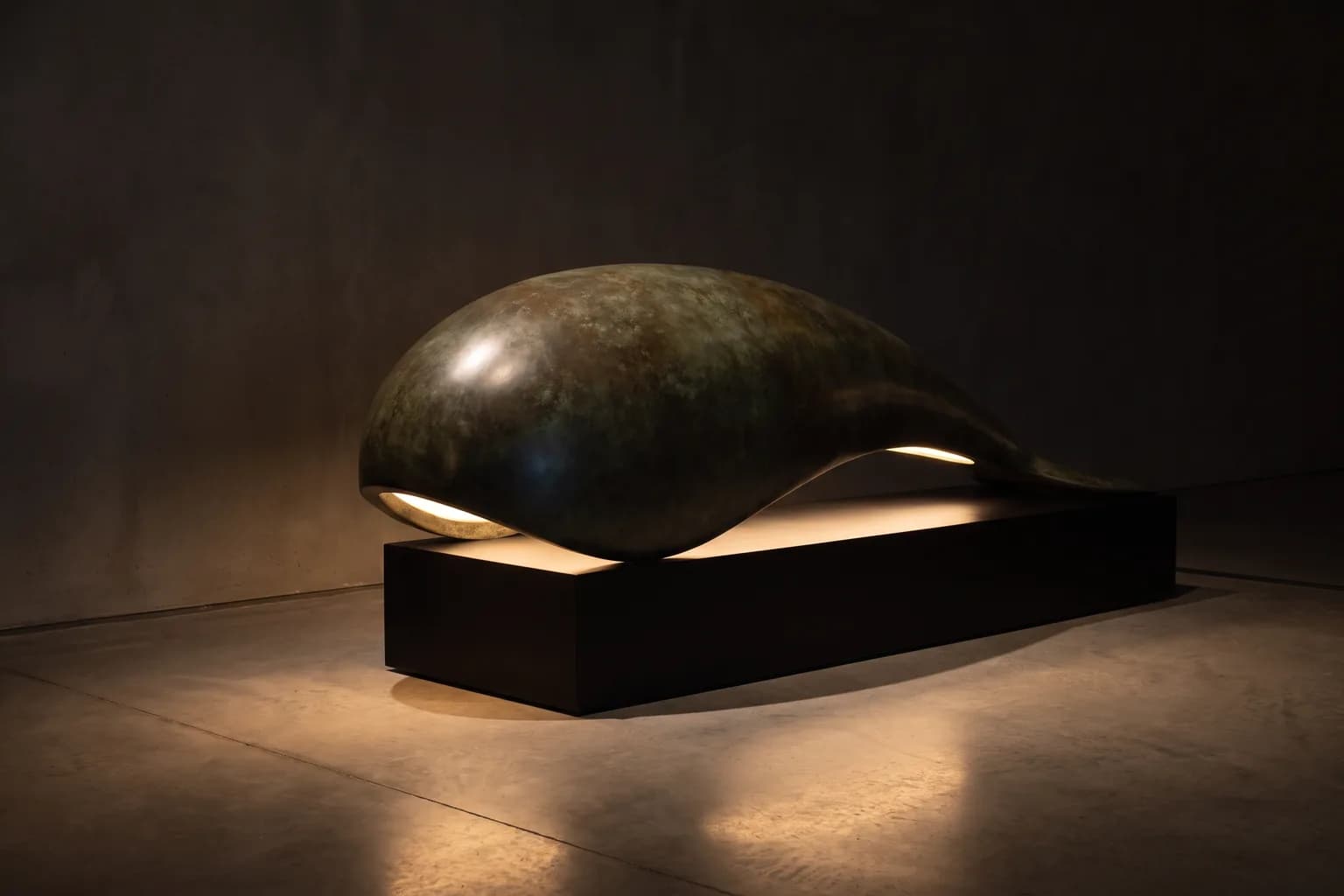 Visualisation éditoriale d'une lampe sculpturale au volume courbe abstrait, en bronze patiné vert-brun